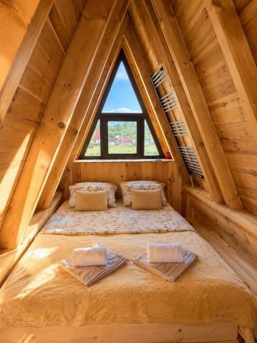 a bed in a wooden room with a window at Jugoslavija Chalet and Spa Zabljak in Tepačko Polje