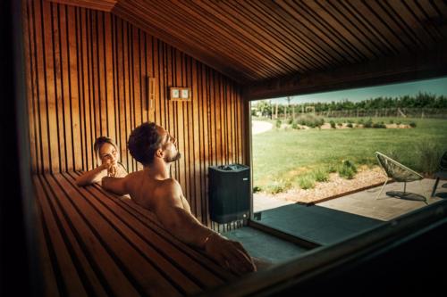two men in a bath tub in a wooden house at Domaine Sur Les Sarts in Ohey
