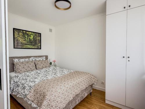 a bedroom with a bed and a white wall at Apartament Biłgorajski przy Rynku in Biłgoraj