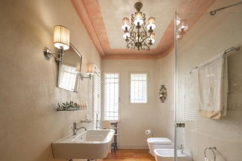 a bathroom with a sink and a mirror and a chandelier at Palazzo Benassi Nobile Dimora nel Cuore di Asolo in Asolo