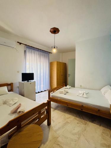 a large room with two beds and a refrigerator at Summer Rooms in Skala Kallirachis