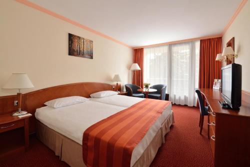 a hotel room with a large bed and a television at Ensana Thermal Sárvár in Sárvár