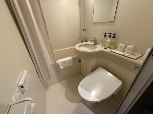 a small bathroom with a toilet and a sink at HOTEL KAN-RAKU Mishima Main Street in Mishima