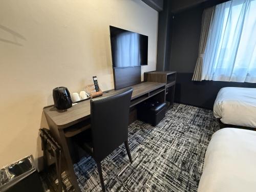 a hotel room with a desk and a bed at HOTEL KAN-RAKU Mishima Main Street in Mishima