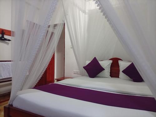 a bedroom with a canopy bed with purple and white pillows at Golden View Guest Ella in Ella