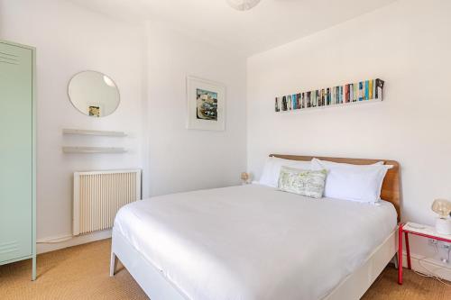 a bedroom with a white bed and a mirror at 2a Coastguard Cottages in Gorran Haven