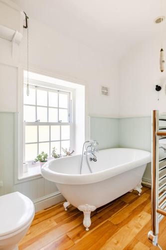 a white bath tub in a bathroom with a window at 2a Coastguard Cottages in Gorran Haven