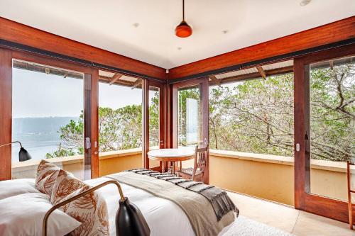 a bedroom with large windows and a bed and a table at Cloud 9 Luxury Eco Villa in Sedgefield