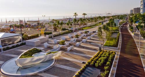 a view of a park with white benches and the beach at Hotel Margareth in Riccione
