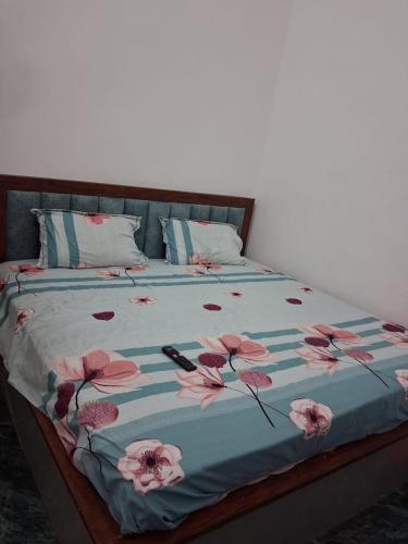 a bed with a blue comforter with pink flowers on it at Hotel Kunj Palace in Etah