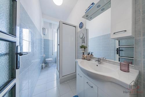 a white bathroom with a sink and a shower at Gramsci House - Sea 3 min - Central - Family in Vado Ligure