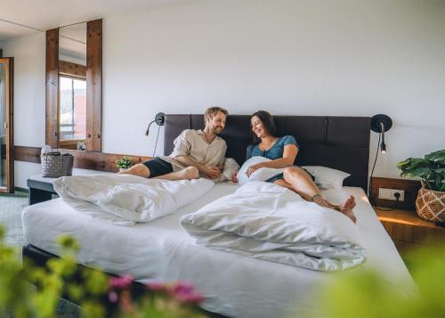 a man and a woman sitting on a bed at Wellnesshotel Linde in Sulzberg