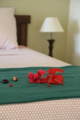a pair of red flowers sitting on a bed at L'Eden des Colibris in Vieux-Habitants