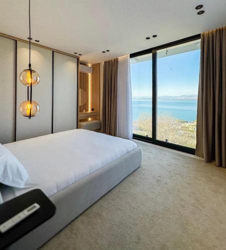 a bedroom with a large bed with a view of the ocean at Vatër by the lake in Shirokë
