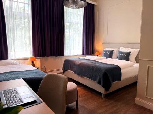 a hotel room with two beds and a laptop on a desk at UNO Smart Hamburg Central 056 in Hamburg