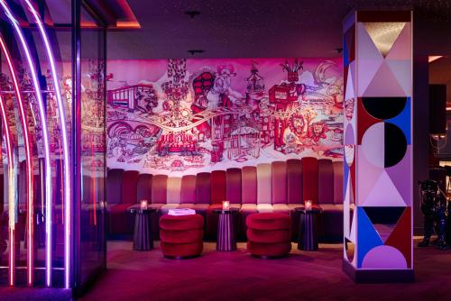 a room with a bar with stools and a mural at NYX Hotel Amsterdam Rembrandt Square in Amsterdam