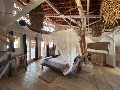a bedroom with a bed with a net in it at SHAYA cottage in Sekotong
