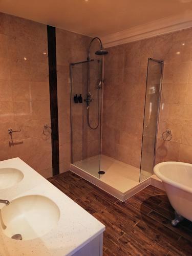 a bathroom with a shower and two sinks and a tub at Chartridge Lodge Hotel in Chesham