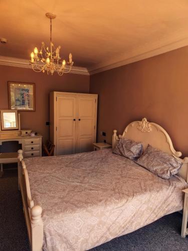 a bedroom with a bed and a chandelier at Chartridge Lodge Hotel in Chesham