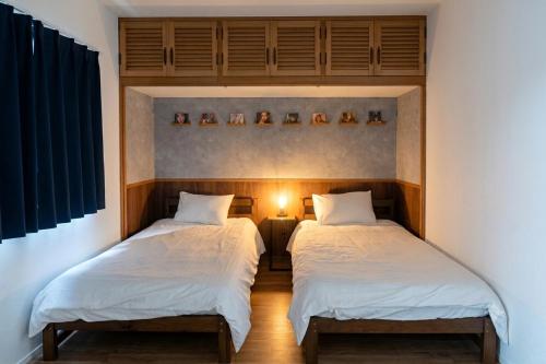 two beds in a bedroom with a light between them at Tomoeドットコム3 music stay in Hakodate