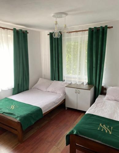 two beds in a room with green curtains at NOCLEGI NOVA in Krasnobród