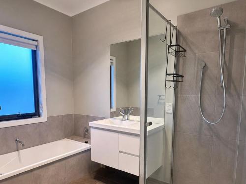 a bathroom with a shower and a sink and a tub at Central 3BR Home in Mansfield