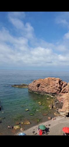 a beach with umbrellas on a rocky island in the ocean at Marina in Tipaza