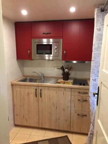 a kitchen with red cabinets and a sink and a microwave at Feriendomizil Bockelmann in Bad Bevensen