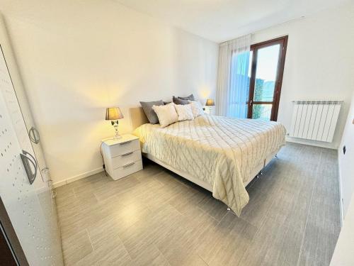 a white bedroom with a bed and a window at Appartamento La Perla in Brezzo