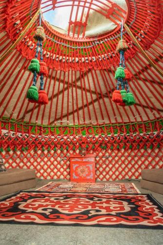 a red and white yurt with a rug in it at Old stones glamping in Chok-Tal