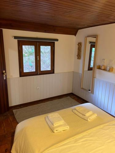 a bedroom with a bed with two towels on it at Bungalow Refúgio do Pezo T1 in Melgaço
