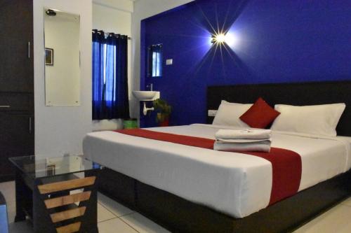 a bedroom with a large bed with a purple wall at Paddyfield Inn in Mananthavady