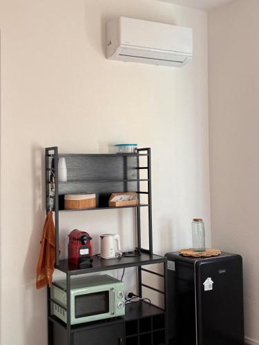 a kitchen with a microwave and a black refrigerator at Nonna Consolata Studio - 25 min to Cagliari & Beaches in Dolianova