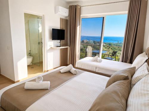 a hotel room with two beds and a large window at Villa Dedi ,Borsh in Vane