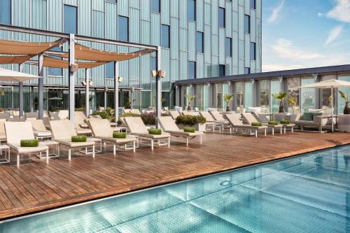 a swimming pool with lounge chairs next to a building at Meliá Barcelona Sky 4 Sup in Barcelona