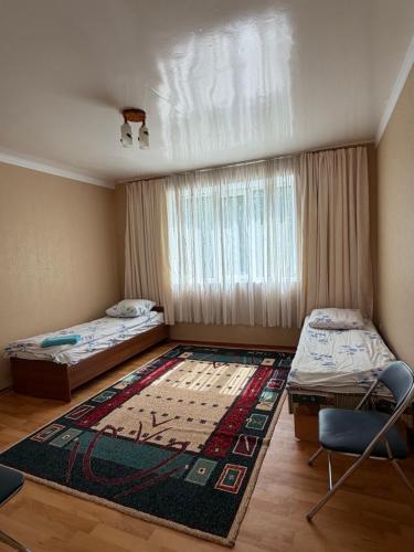 a room with two beds and a rug on the floor at Алтын Мезгил in Korumdy