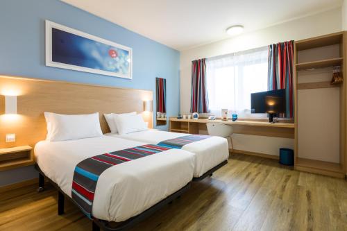 a hotel room with a large bed and a desk at Travelodge Barcelona Fira in Hospitalet de Llobregat