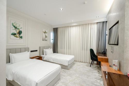 a hotel room with two beds and a desk at Meridian Plaza by Reikartz in Samarkand
