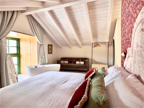 a bedroom with a large white bed and a tub at La Casa de las Flores in Noceda del Bierzo