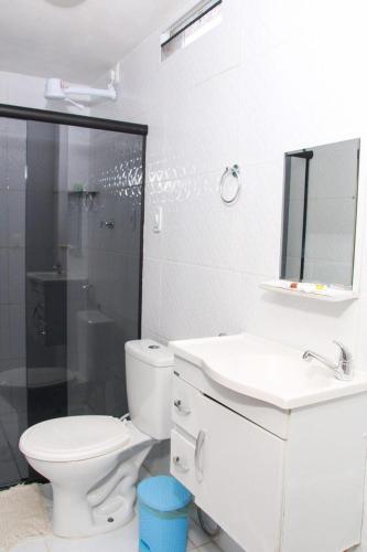 a white bathroom with a toilet and a sink at Pousada Sereias de Maragogi in Ponta do Mangue