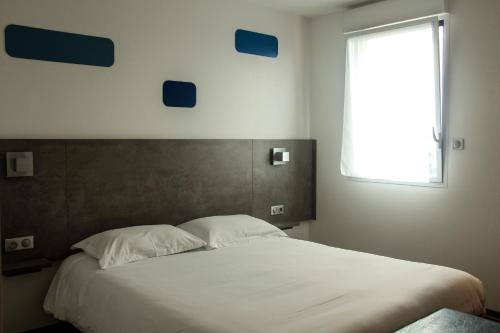 a bedroom with a large bed with a window at H24 HOTEL in Le Mans