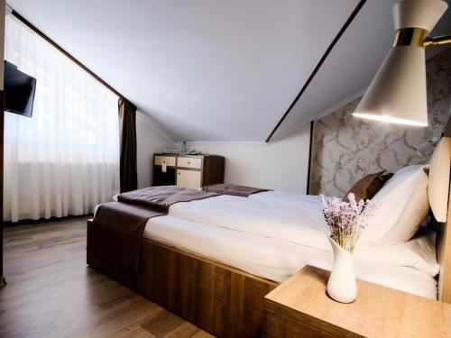 a bedroom with a bed and a vase of flowers on a table at Hotel Poezia in Luna