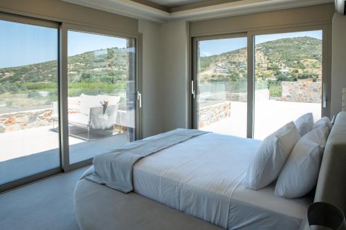 a bedroom with a bed and a large window at Stone Luxury Suites in Agioi Apostoli