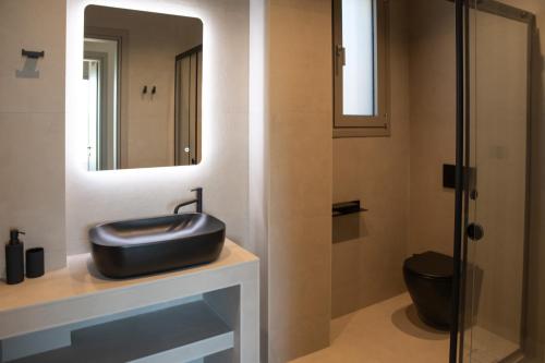 a bathroom with a black sink and a mirror at Stone Luxury Suites in Agioi Apostoli