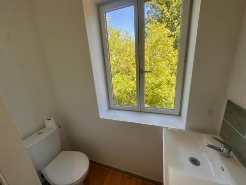 a bathroom with a toilet and a sink and a window at Le loft sous les colombages in Gouffern en Auge