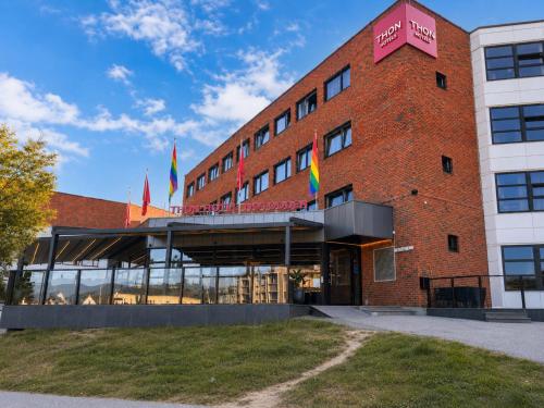 a red brick building with flags in front of it at Thon Hotel Notodden in Notodden