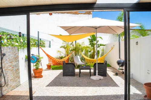 a patio with chairs and an umbrella and hammocks at Casa Elegante V3 Moderna 2 Suítes, Jardim e Garagem Privados in Olhão