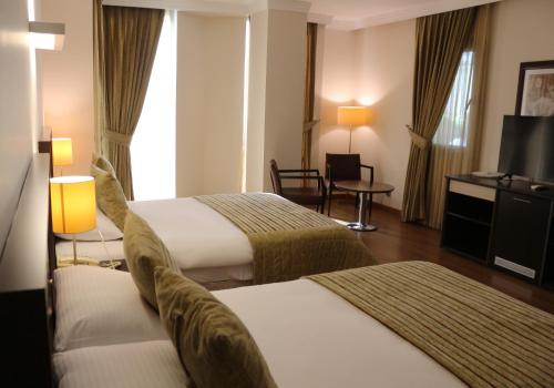 a hotel room with two beds and a television at Akkoç Butik Otel in Seyhan