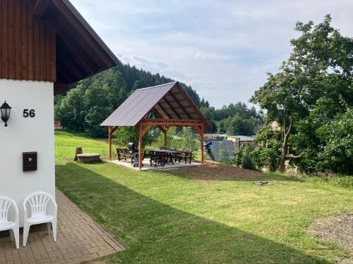 a pavilion with a picnic table and chairs in a yard at Chalupa a apartmány Lojka in Benecko