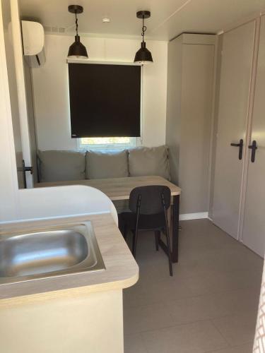 a kitchen with a couch and a table with a sink at Càmping Vila Village in Sant Feliu de Buixalleu